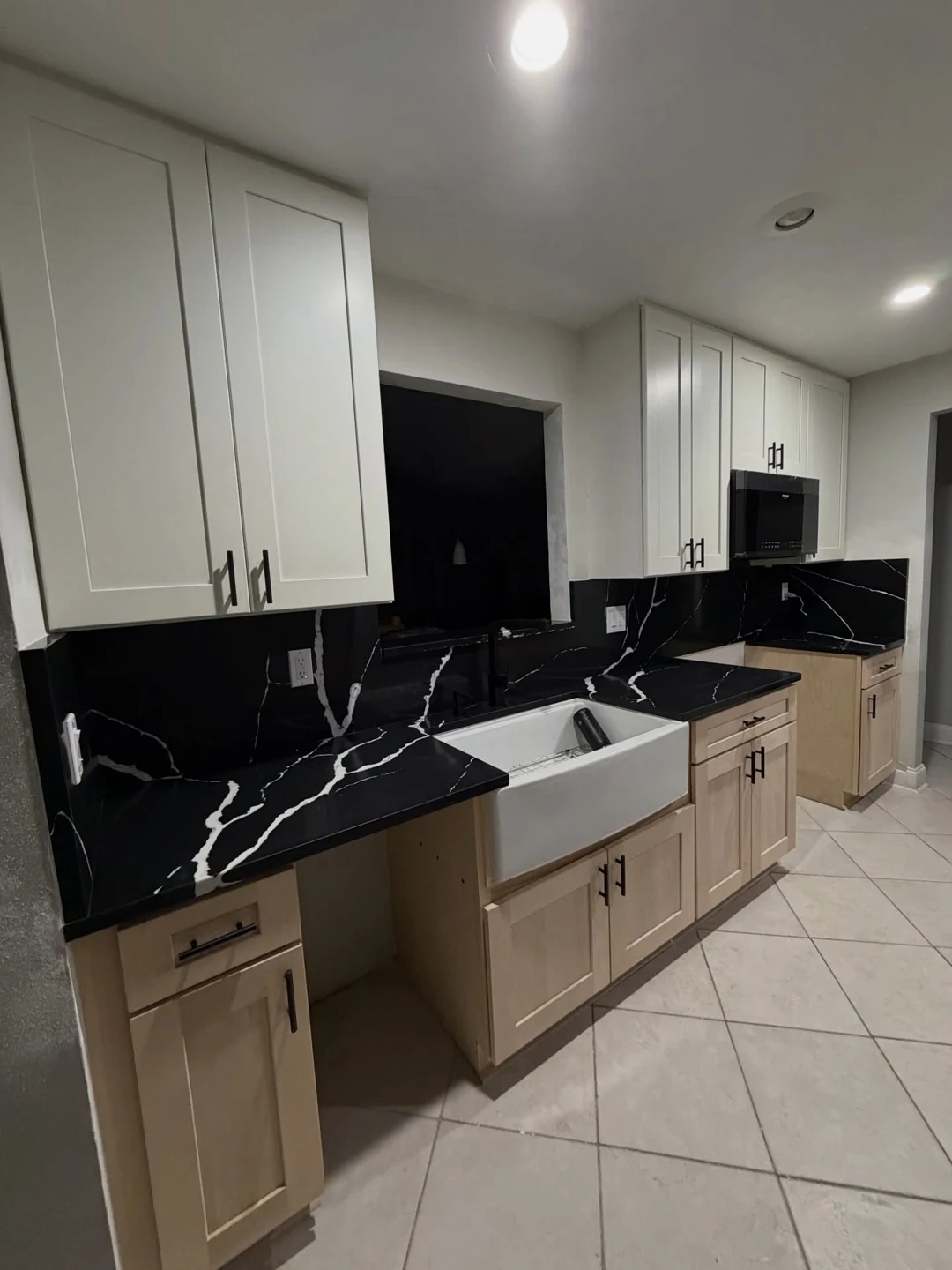 White kitchen cabinets, a dark veined countertop and wood-toned lower cabinets
